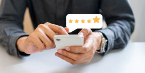 close up on businessman hand pressing on smartphone screen with gold five star rating