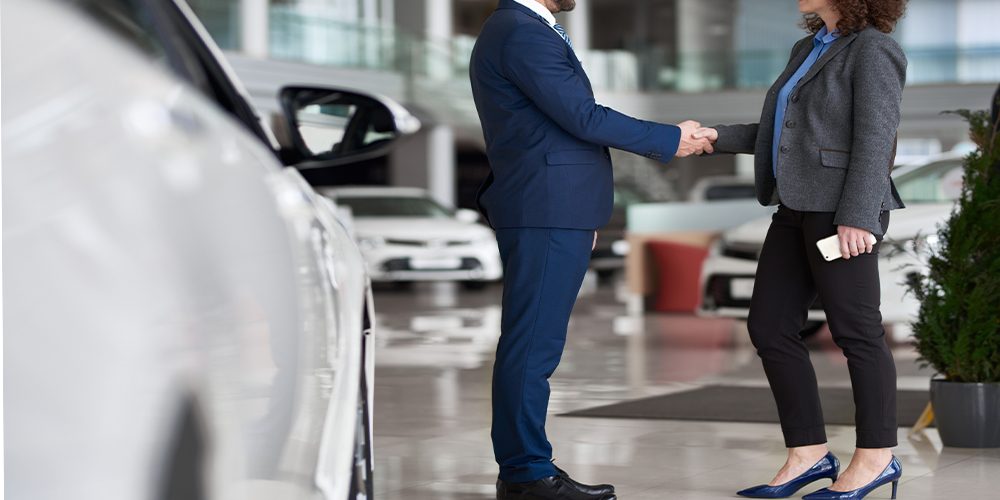 Man and woman shaking hands in auto dealership